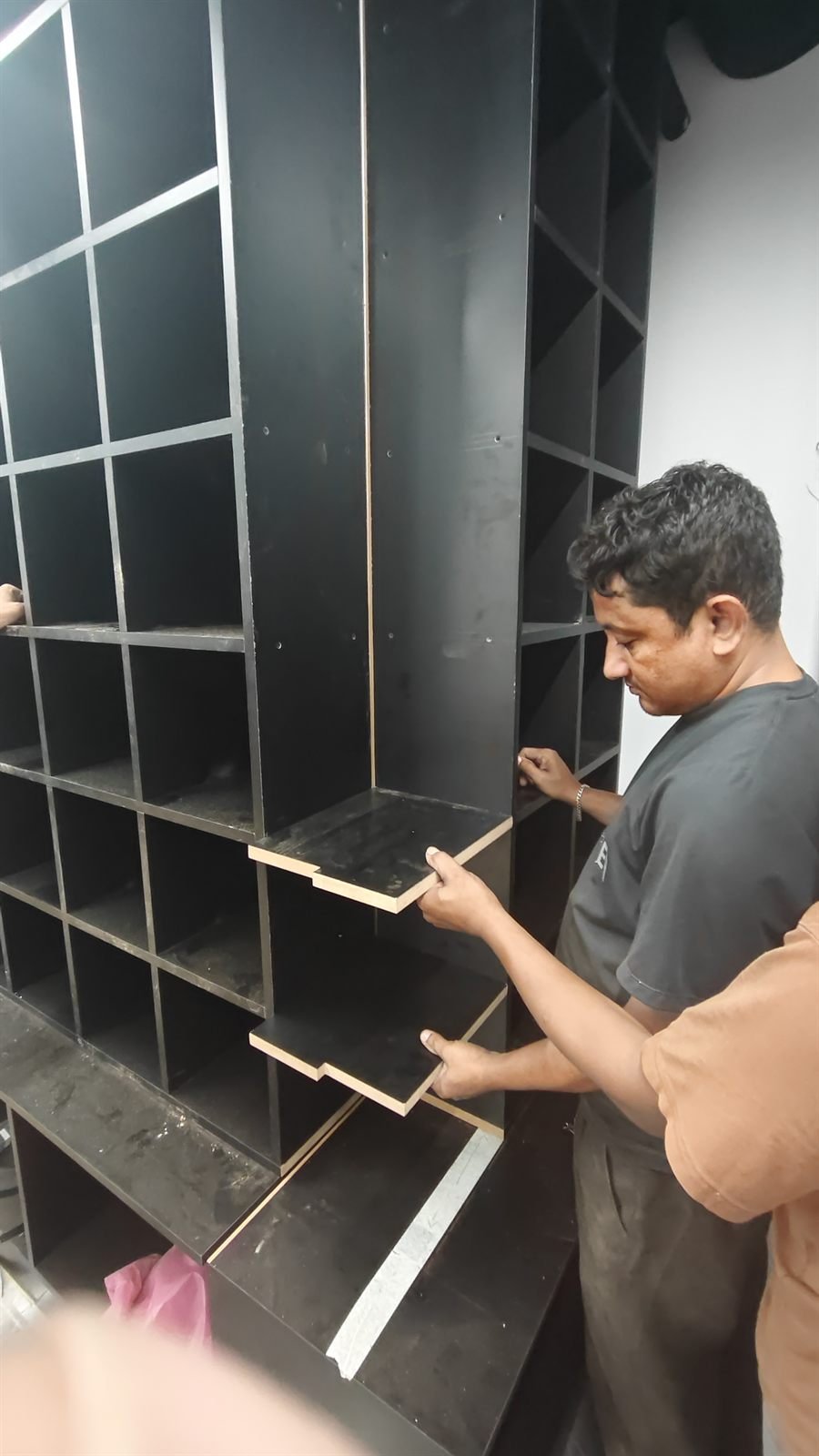 Carpenter fitting black display shelves on site, Dubai